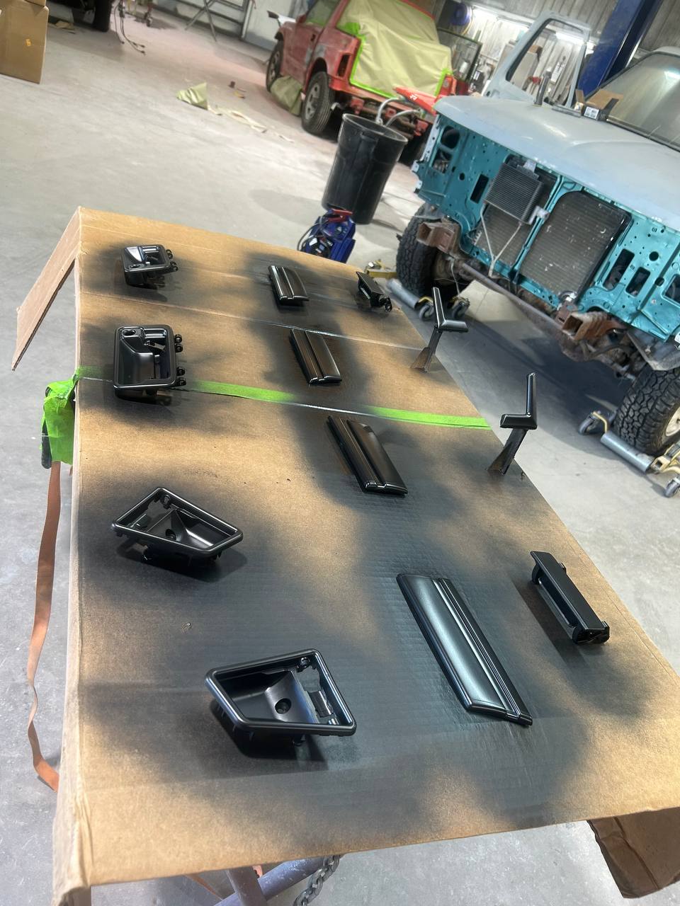 Jeep Wrangler trim pieces handles and hardware freshly painted laid out during frame-off restoration at The Drip