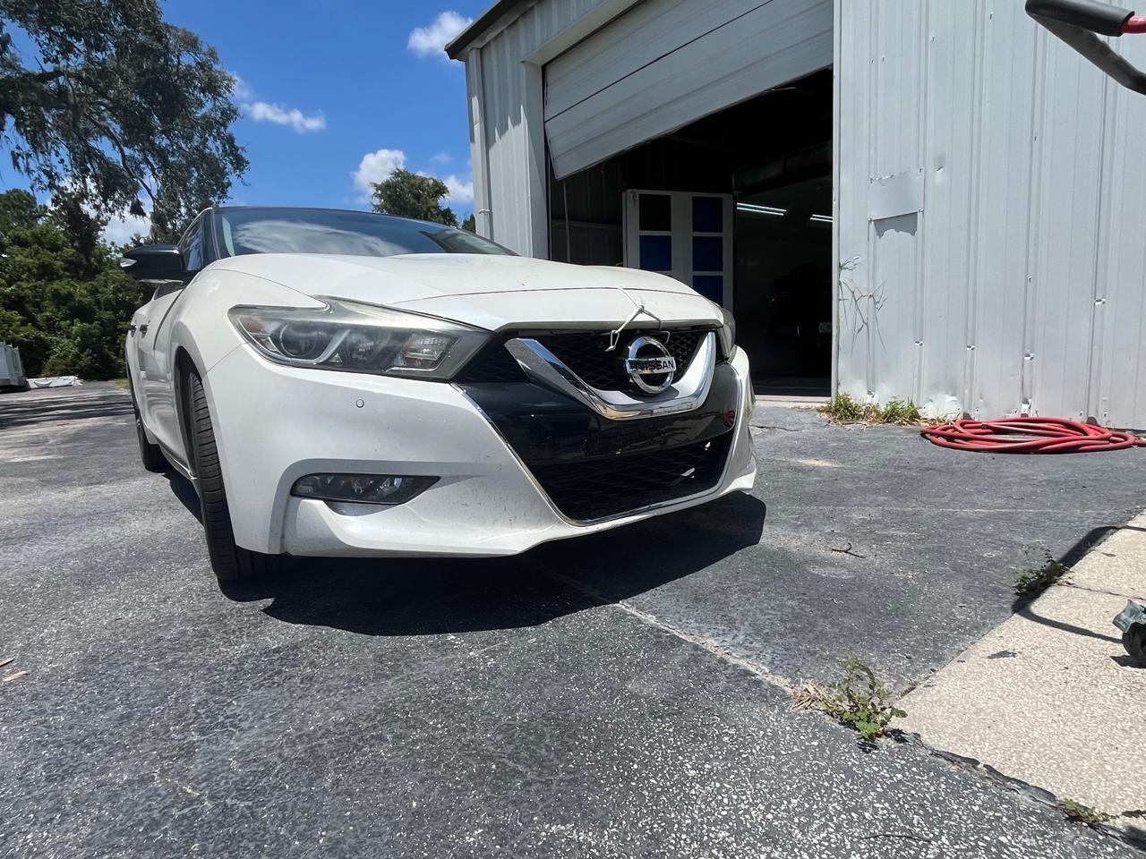 Nissan Maxima Platinum completed collision repair - low angle front view outside shop at The Drip