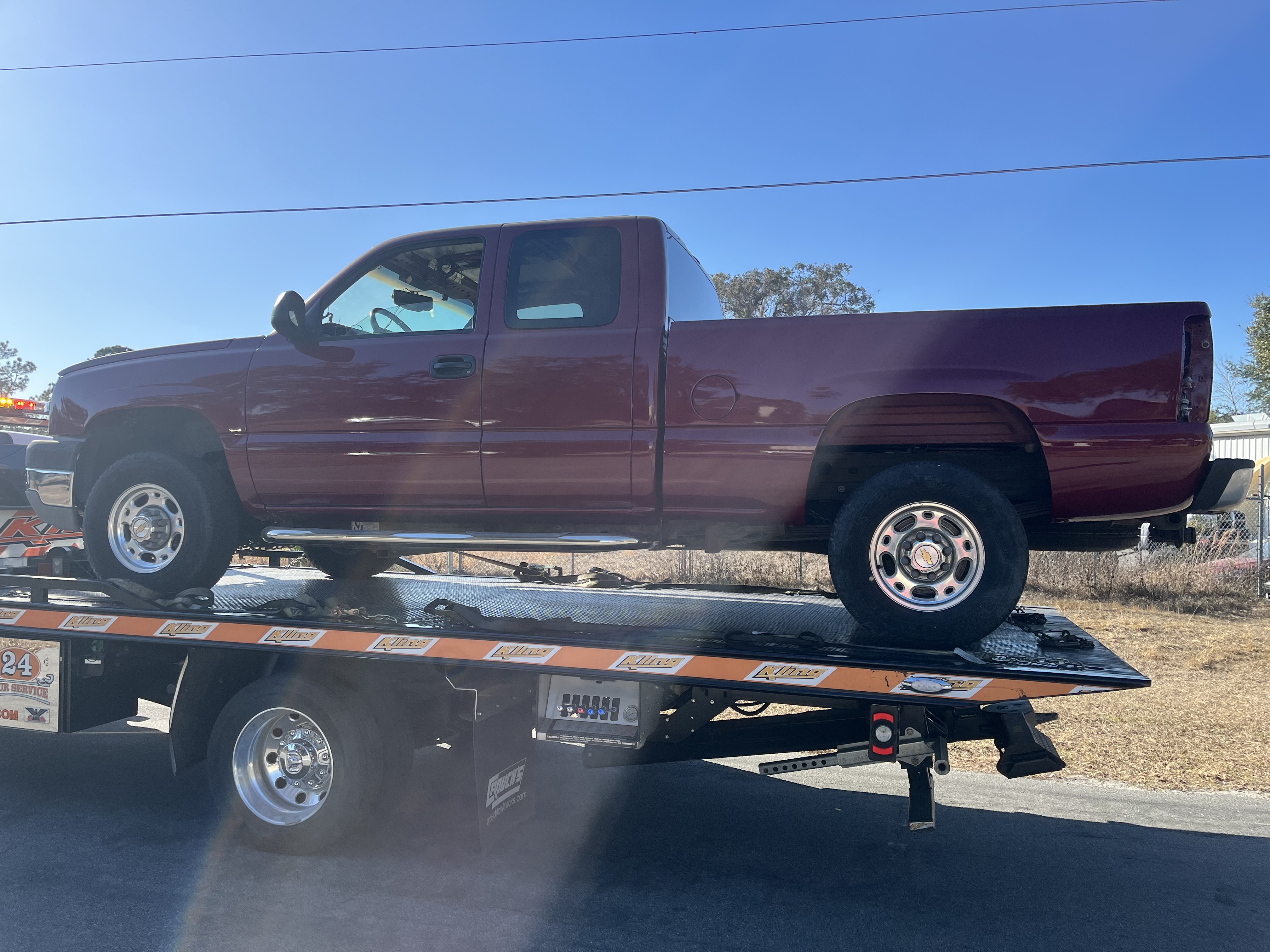 Chevy Silverado extended cab arriving on flatbed for collision repair at The Drip Auto Body Leesburg FL