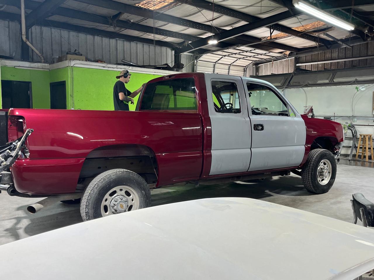 Chevy Silverado technician working on door panels - primer to paint process at The Drip Auto Body