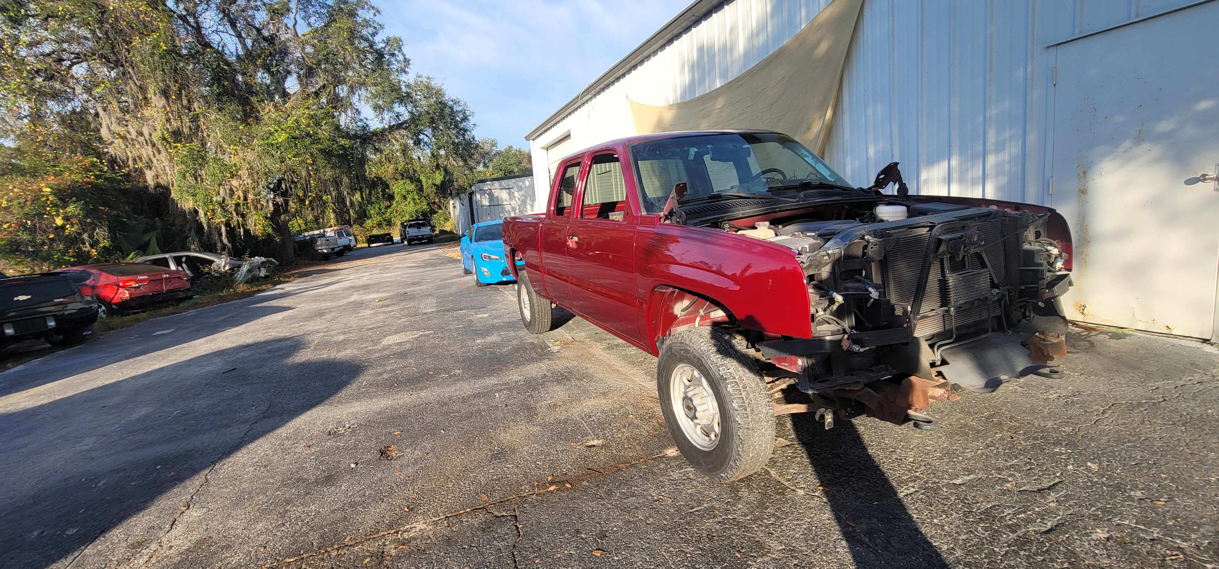 Chevy Silverado front end stripped for full rebuild - fresh red paint on cab and bed at The Drip Auto Body Leesburg FL