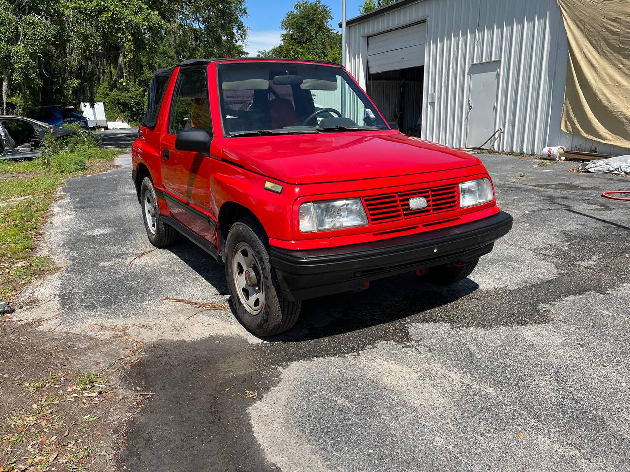 Geo Tracker front view completed red paint job outside The Drip Auto Body shop